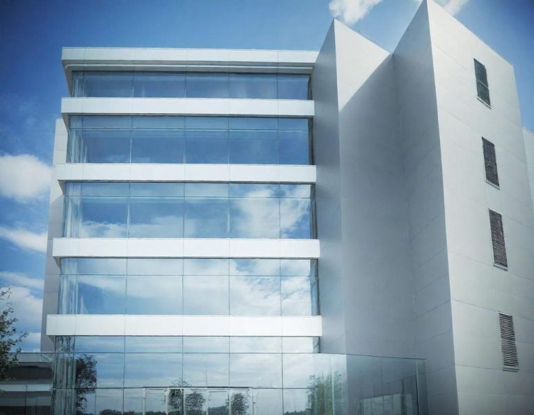 Bâtiment moderne à façade en verre avec ciel bleu en arrière-plan.