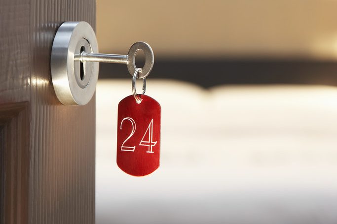 Clé rouge avec le numéro 24 accrochée à une serrure en bois.