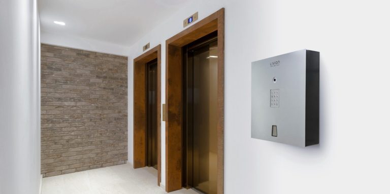 Deux portes d'ascenseur en bois dans un couloir contemporain, avec une armoire à clés murale.