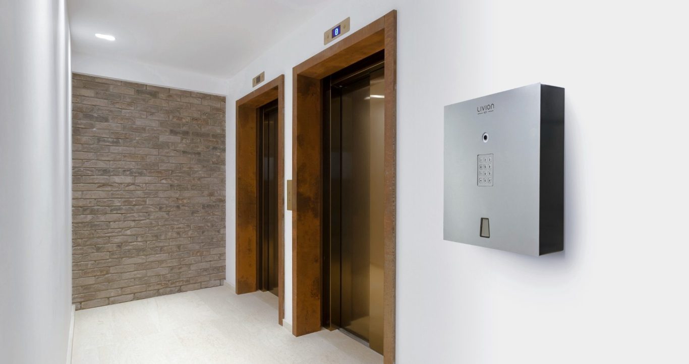 Un couloir d'hôtel avec deux portes d'ascenseur et un distributeur automatique de clés LivionKey30.